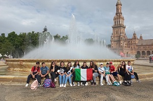 Foto di gruppo degli studenti italiani con la bandiera tricolore davanti alla fontana al centro di Piazza di Spagna, Siviglia